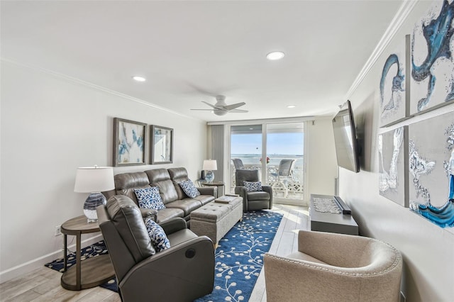 living area featuring baseboards, light wood-style floors, a ceiling fan, and crown molding