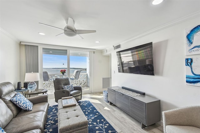 living room with light wood-type flooring, visible vents, a ceiling fan, and ornamental molding