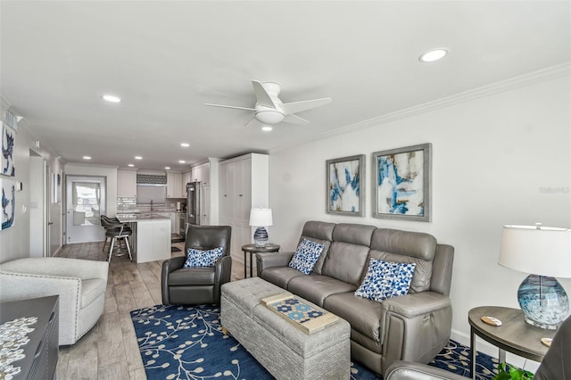 living room featuring light wood finished floors, ceiling fan, crown molding, and recessed lighting