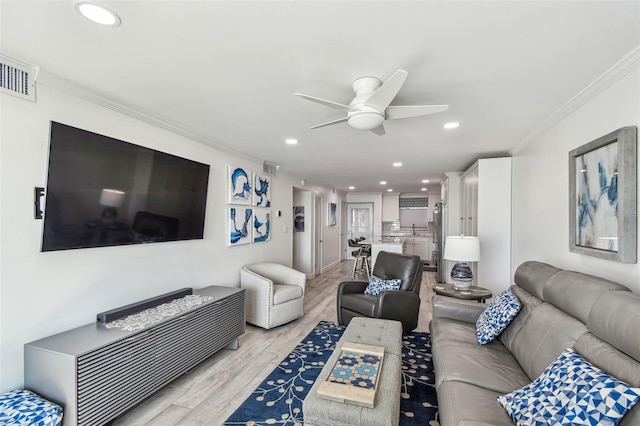 living area featuring recessed lighting, visible vents, ornamental molding, a ceiling fan, and light wood-type flooring