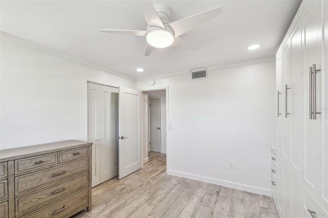 unfurnished bedroom with a closet, visible vents, ornamental molding, light wood-type flooring, and baseboards