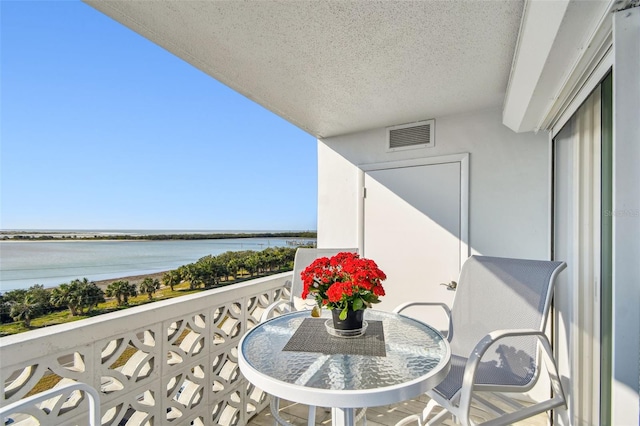 balcony featuring a water view, visible vents, and outdoor dining area