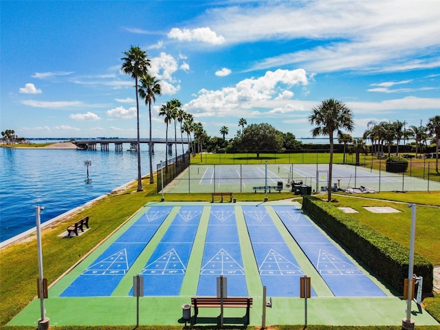 view of community with a water view, shuffleboard, fence, and a yard