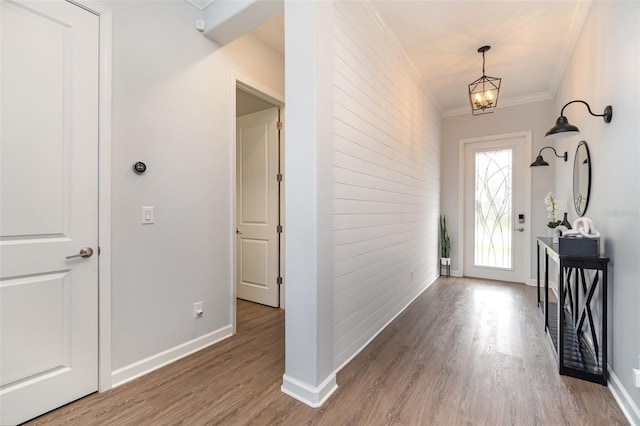 entrance foyer with wood-type flooring, an inviting chandelier, and crown molding