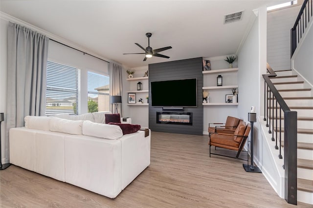 living room with ceiling fan, ornamental molding, light hardwood / wood-style floors, and a fireplace