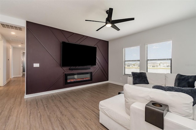 living room featuring ceiling fan, wood-type flooring, and a fireplace