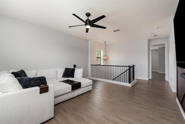 living room with dark hardwood / wood-style flooring and ceiling fan with notable chandelier