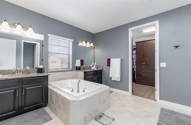 bathroom with a relaxing tiled tub, tile patterned floors, and vanity