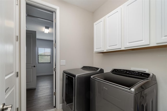 laundry room featuring hardwood / wood-style flooring, washing machine and clothes dryer, and cabinets