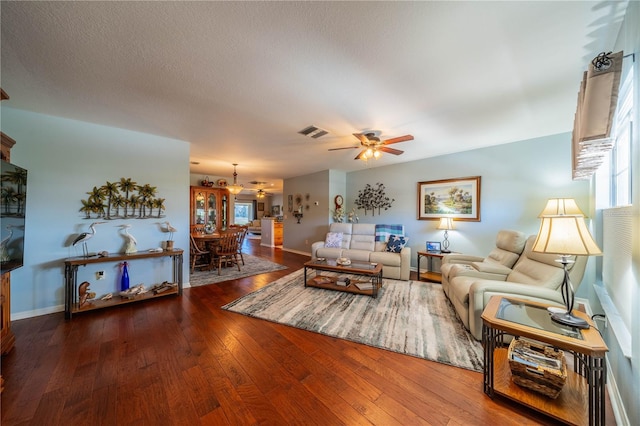 living room with a textured ceiling, dark hardwood / wood-style floors, and ceiling fan