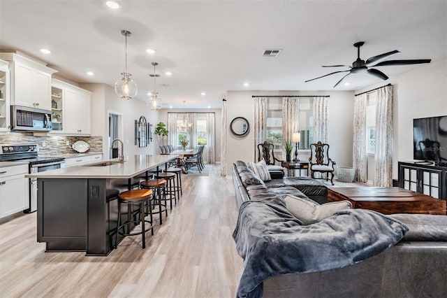 living room with sink, ceiling fan, and light hardwood / wood-style floors