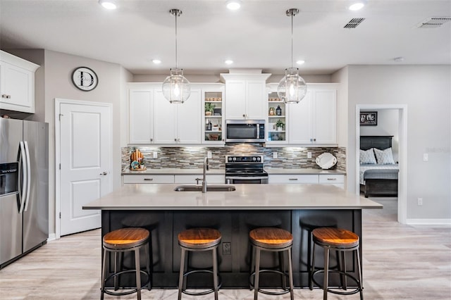 kitchen with decorative light fixtures, an island with sink, appliances with stainless steel finishes, and sink