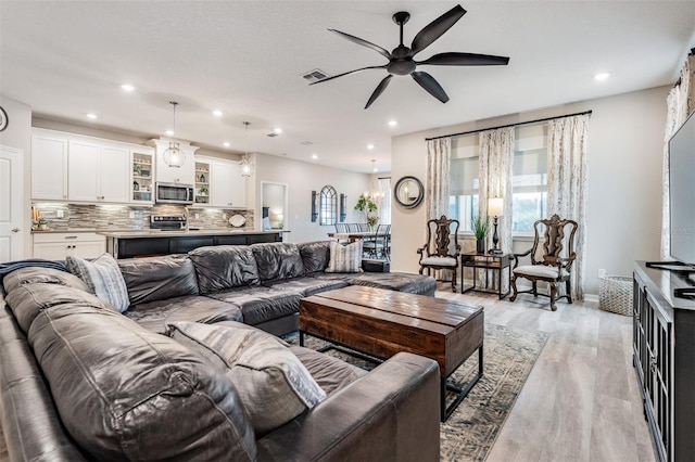 living room with ceiling fan and light hardwood / wood-style flooring