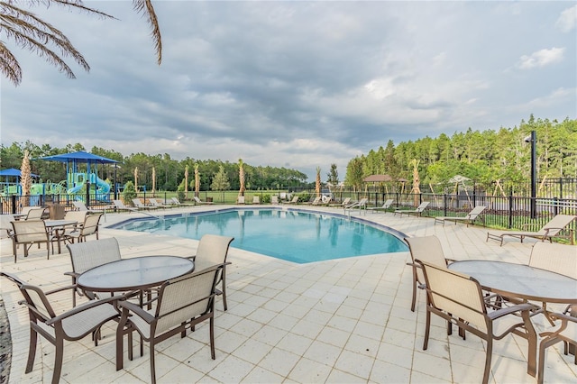 view of swimming pool with a playground and a patio