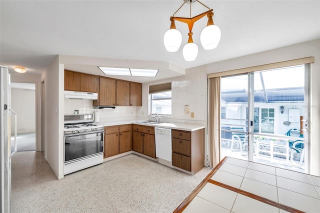 kitchen with hanging light fixtures, sink, white appliances, and decorative backsplash