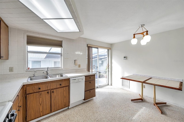 kitchen with sink, hanging light fixtures, white dishwasher, stove, and backsplash