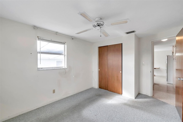 unfurnished bedroom featuring stainless steel refrigerator, ceiling fan, and a closet