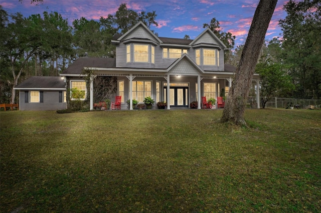 view of front of home featuring an outbuilding, covered porch, and a lawn