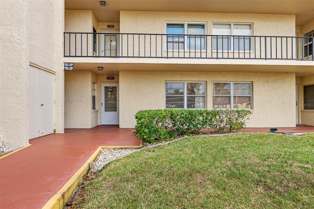 view of exterior entry with a balcony and a lawn