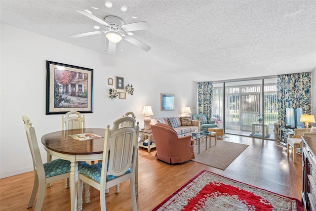 dining room with a textured ceiling, ceiling fan, expansive windows, and hardwood / wood-style floors