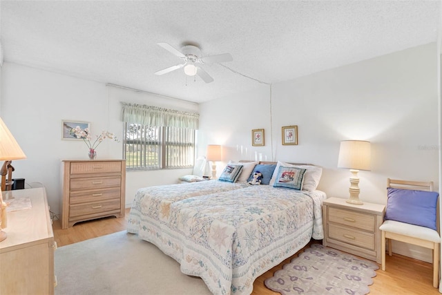 bedroom with a textured ceiling, ceiling fan, and light hardwood / wood-style floors