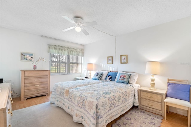 bedroom featuring a textured ceiling, ceiling fan, and light wood-type flooring