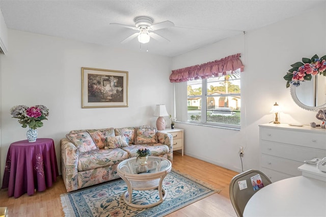 living room with a textured ceiling, ceiling fan, and light hardwood / wood-style floors