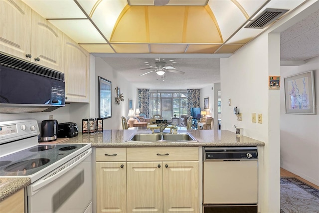 kitchen with white appliances, kitchen peninsula, light brown cabinetry, ceiling fan, and sink