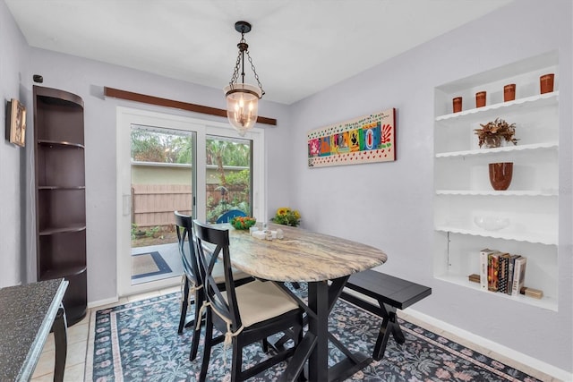 dining space featuring tile patterned floors, a chandelier, and built in shelves