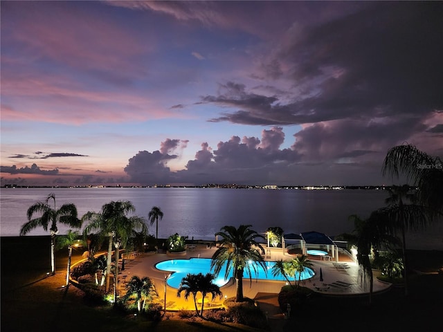 pool at dusk featuring a water view