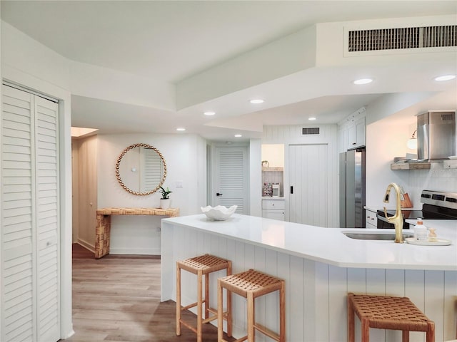 kitchen featuring appliances with stainless steel finishes, kitchen peninsula, a breakfast bar area, and white cabinets