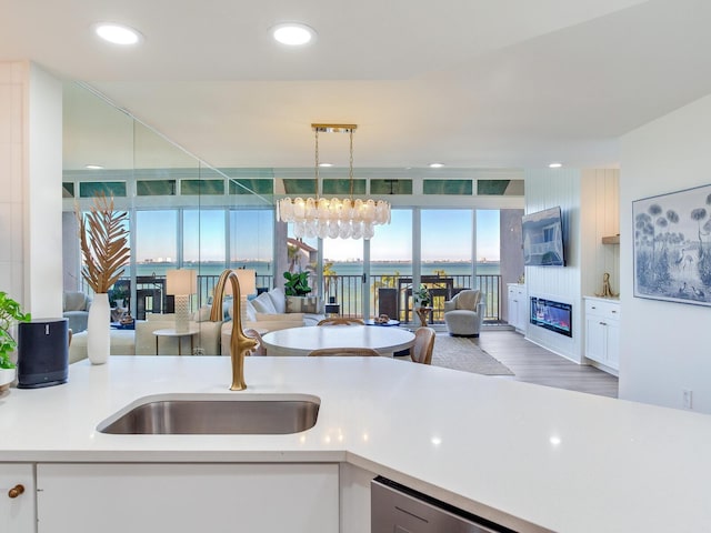 kitchen featuring white cabinetry, sink, a wall of windows, and decorative light fixtures