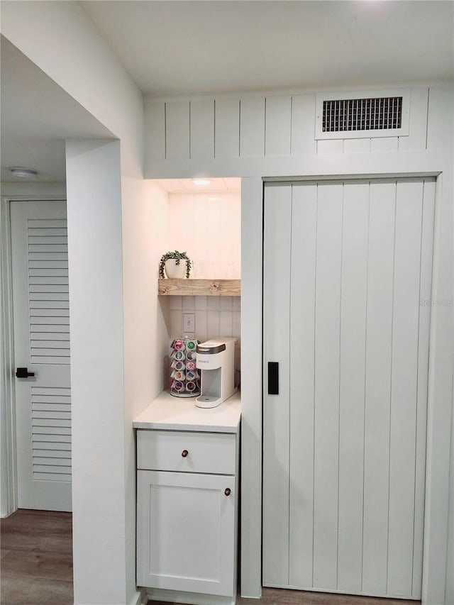 bar featuring light hardwood / wood-style flooring and white cabinets