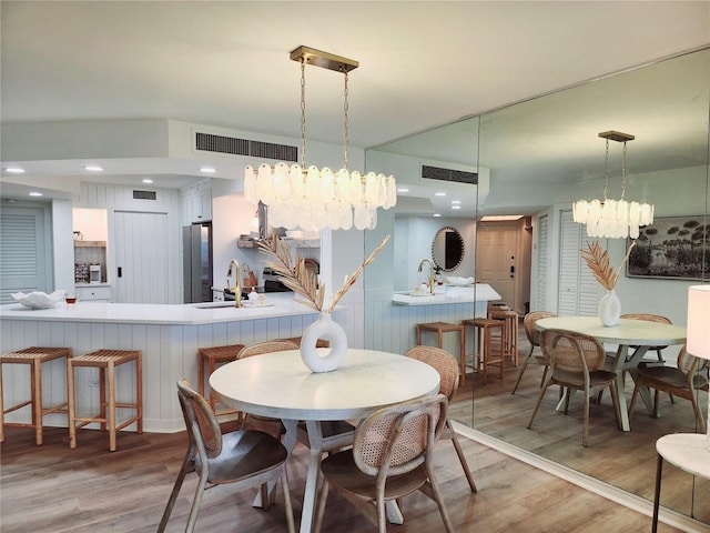 dining area featuring wood-type flooring, a chandelier, and sink