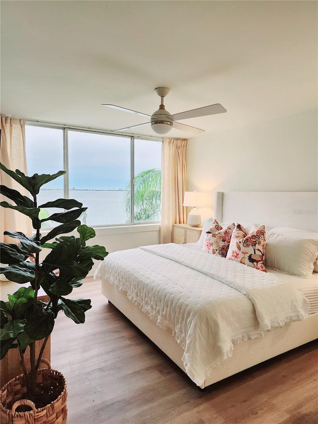 bedroom featuring a water view, ceiling fan, and hardwood / wood-style flooring