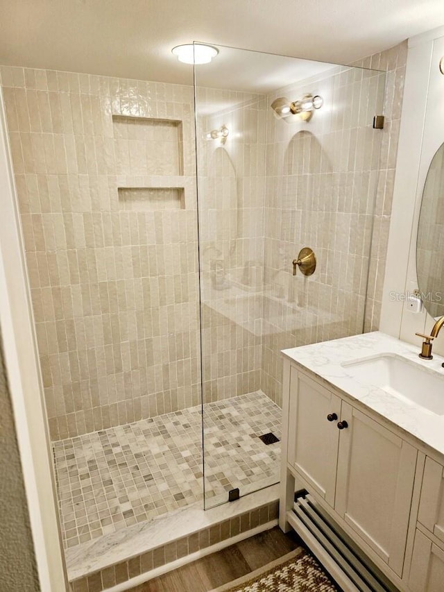 bathroom featuring hardwood / wood-style flooring, vanity, and tiled shower