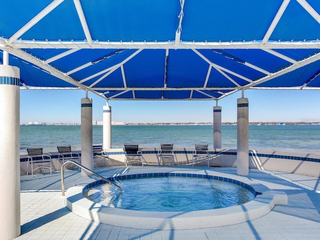 view of swimming pool featuring a water view and an in ground hot tub