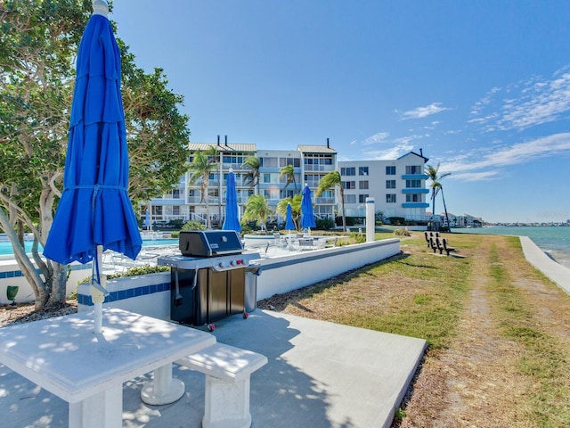 view of community with a water view, a yard, and a patio area