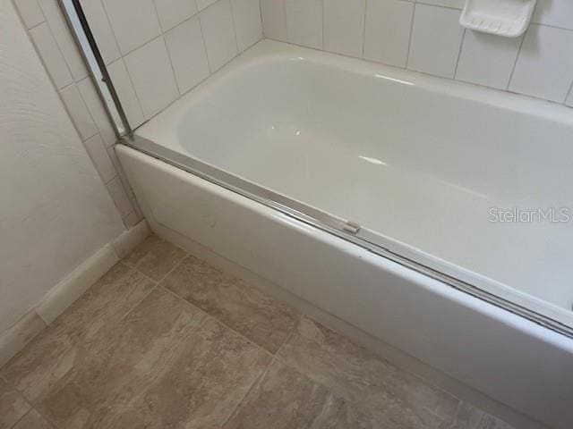 interior space with a bathtub and baseboards