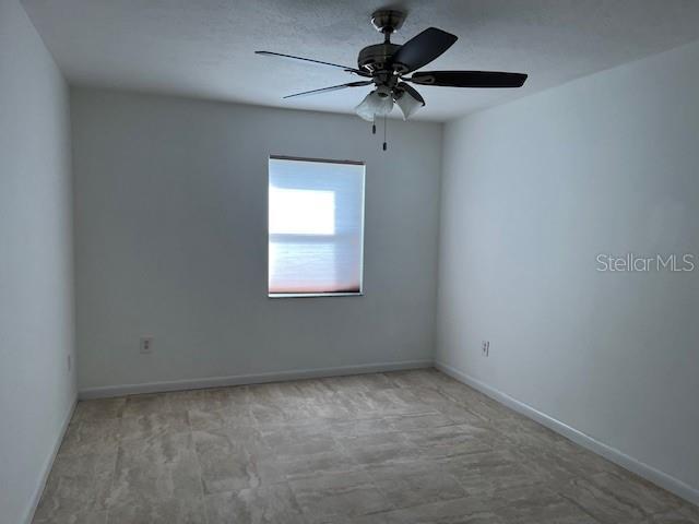 unfurnished room featuring ceiling fan and baseboards