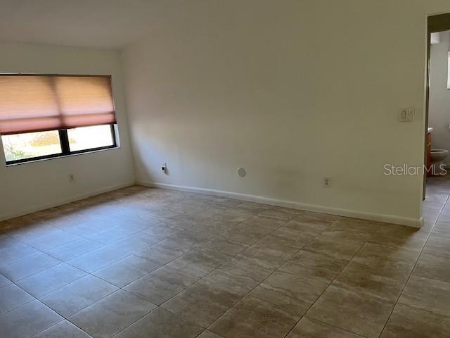 tiled spare room featuring baseboards