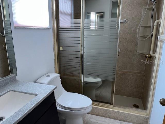 bathroom featuring toilet, a shower stall, and vanity