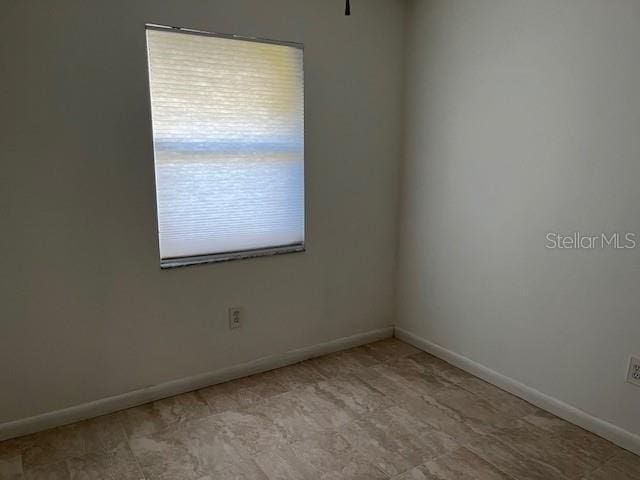 unfurnished room with baseboards