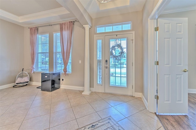 foyer with crown molding, decorative columns, a raised ceiling, and light tile patterned flooring