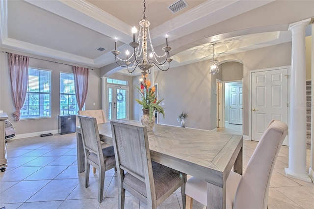 tiled dining room featuring an inviting chandelier, a tray ceiling, crown molding, and ornate columns