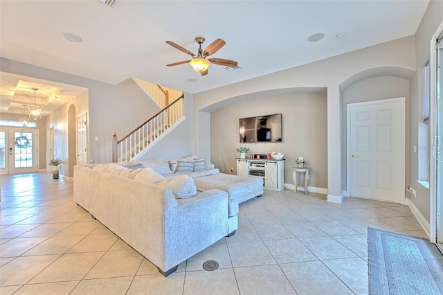 living room featuring ceiling fan with notable chandelier, french doors, and light tile patterned flooring