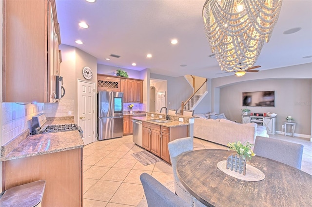 kitchen featuring tasteful backsplash, an island with sink, sink, light tile patterned floors, and stainless steel appliances