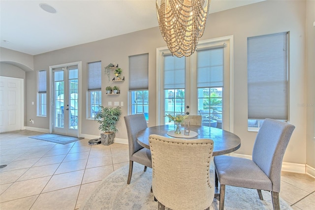 tiled dining room with french doors and a notable chandelier