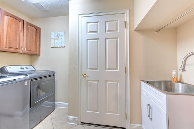 laundry area featuring sink, cabinets, light tile patterned floors, independent washer and dryer, and a textured ceiling