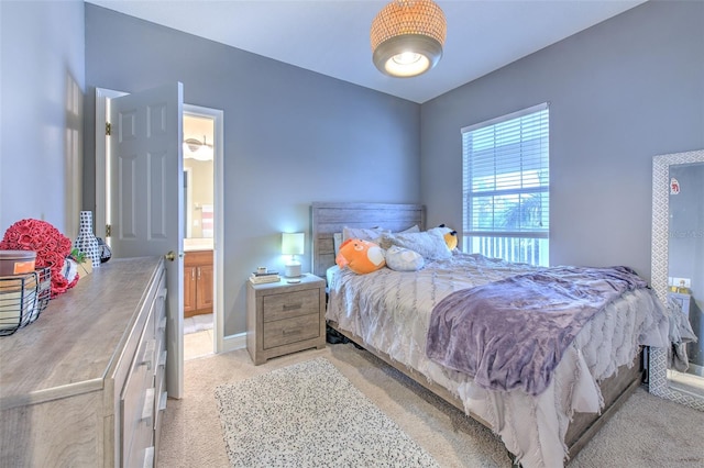 bedroom featuring connected bathroom and light colored carpet